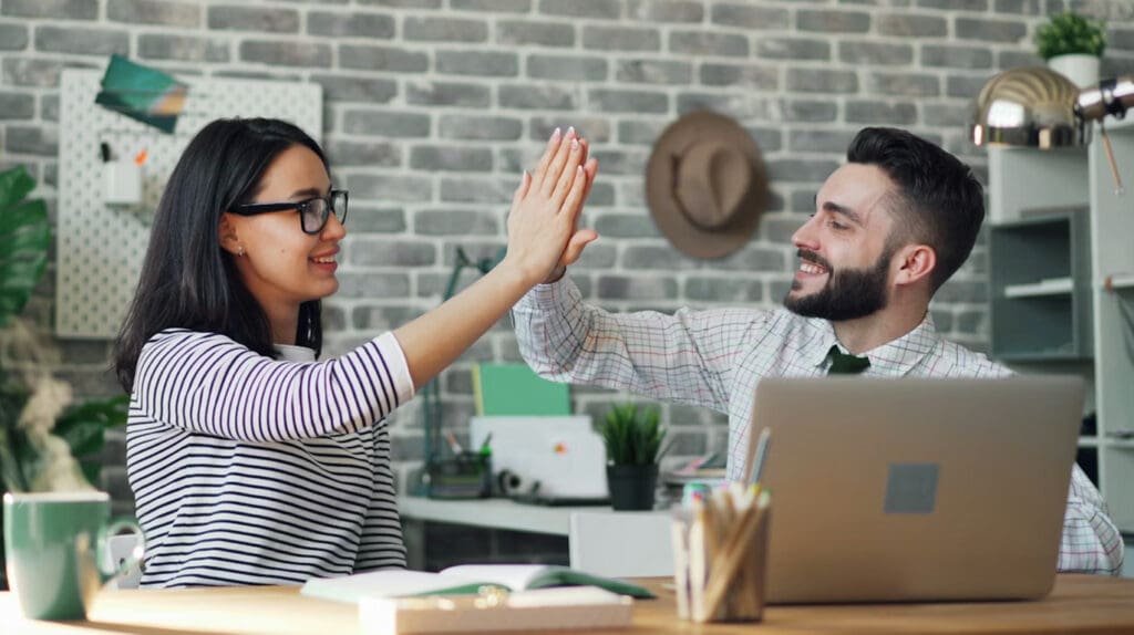 Two people high-fiving in an office setting (A visionary CEO and an Anchored COO working on their 90-day plan)